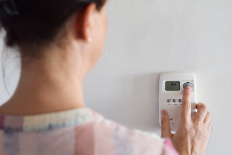 Woman adjusting thermostat settings